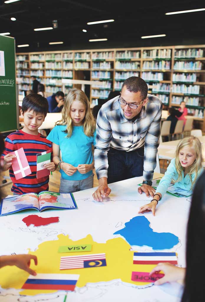 male student showing group of young children countries on map