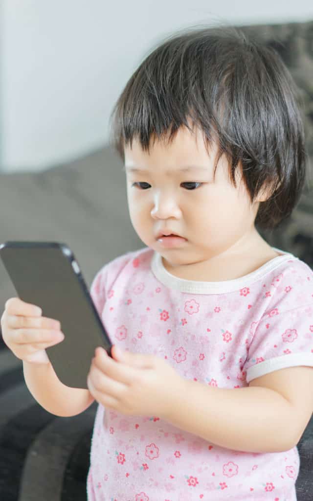 asian toddler holding phone