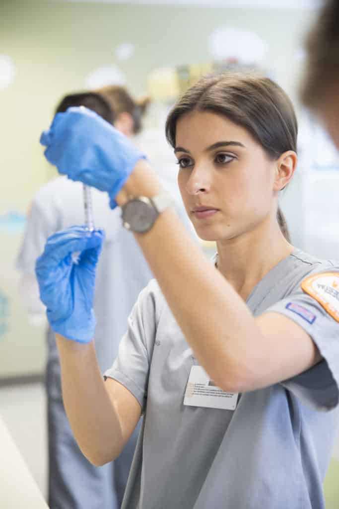 brunette female nurse pulls vaccine into syringe