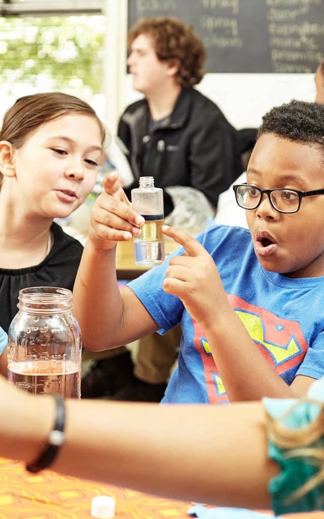 black male elementary student doing science experiment with girl classmate