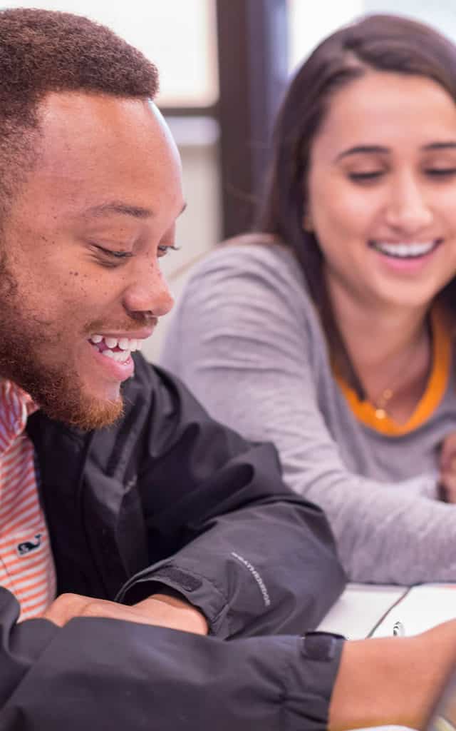 black male and female student smiling while studying
