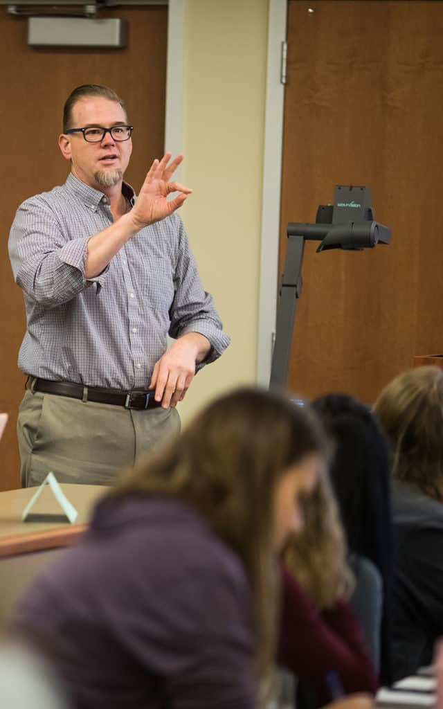 male professor using American sign language while teaching course