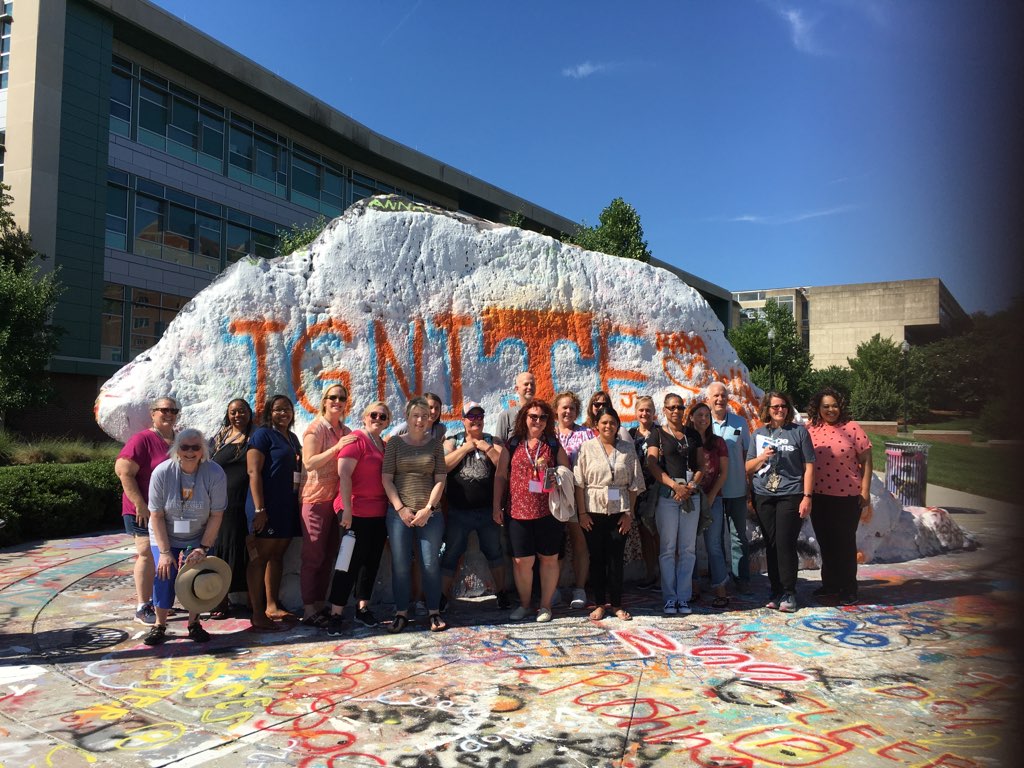 online social work students stand in front of the rock painted to say ignite
