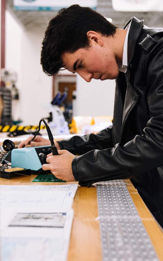 white male student working on electrical soldering iron