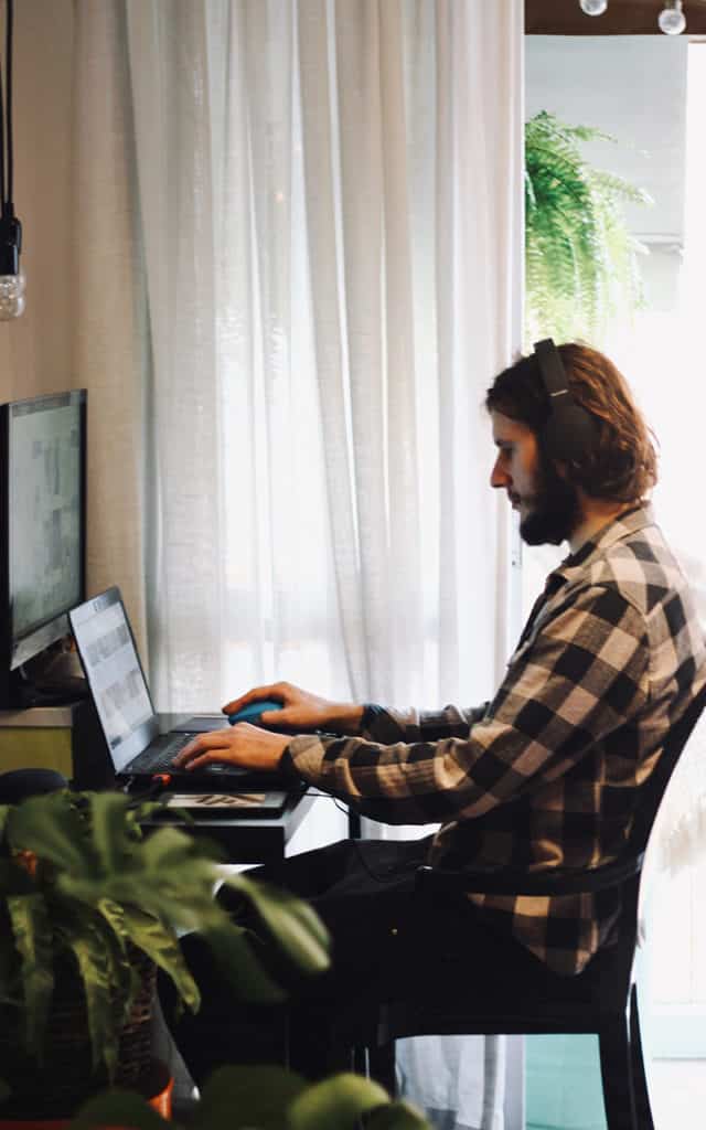white male with beard and long hair working on computer at desk