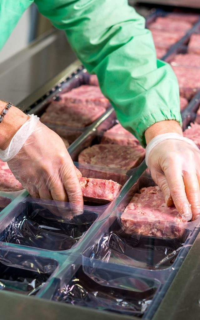 gloved hands packaging meat 