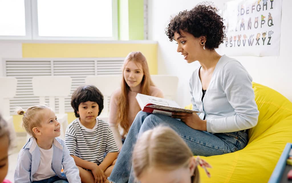 young female teacher reading to group of students