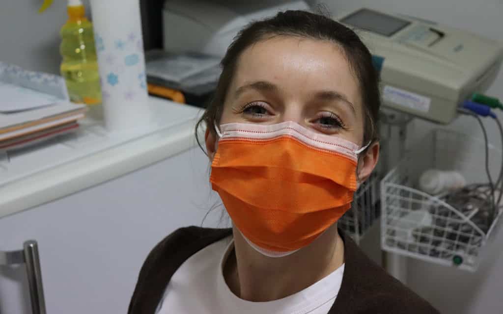 white female patient wearing orange mask in doctor office 
