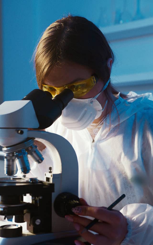 female using microscope with safety goggles 