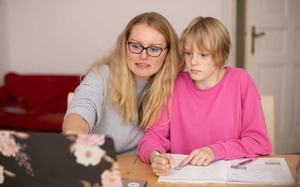 white female educator with glasses helping student in pink shirt at computer