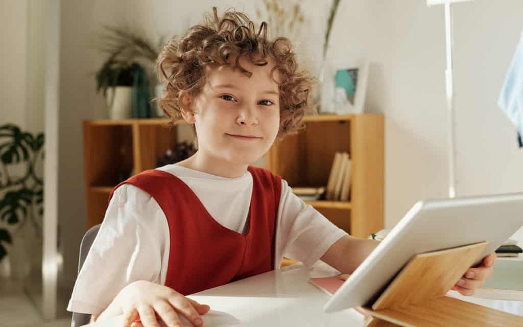 child working on tablet at table