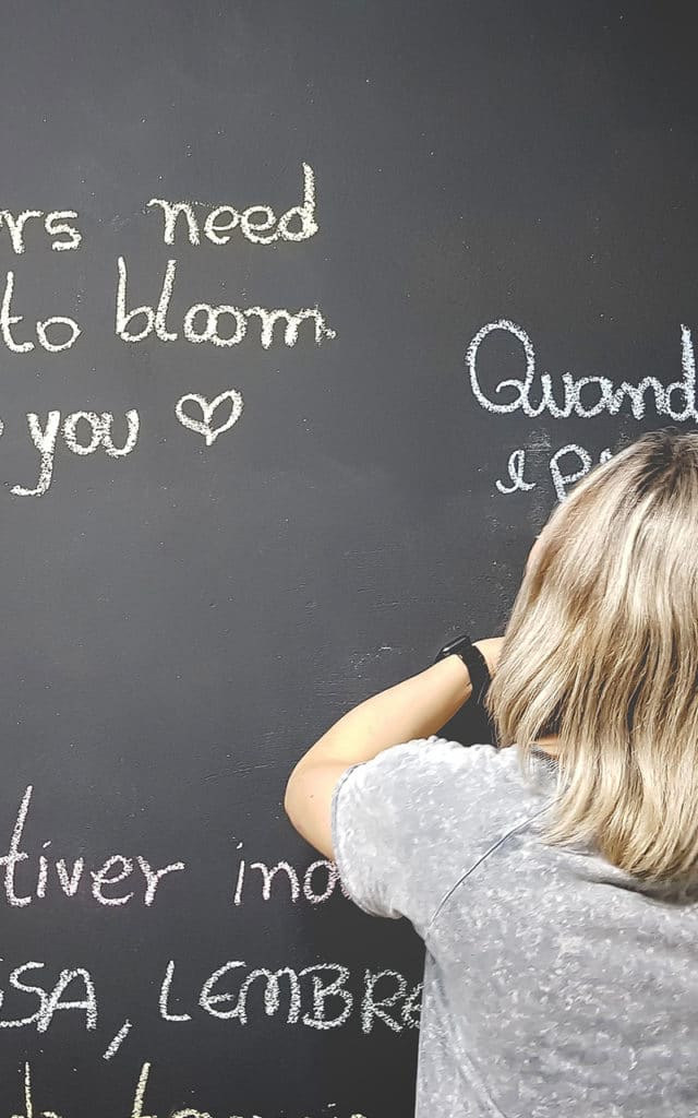student with short blonde hair writing on chalkboard