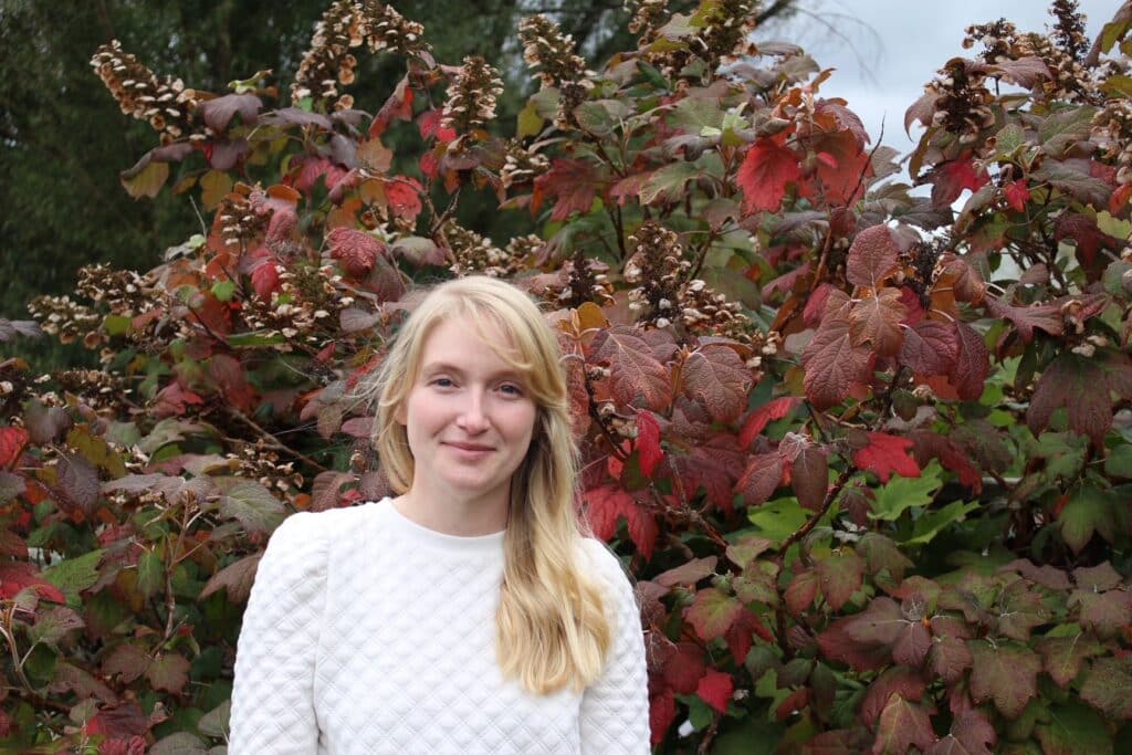 online information sciences student, Esther Dowell, smiling in front of changing leaves