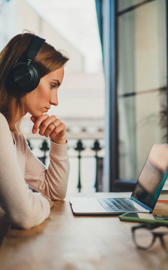 female student wearing headphones while attending online class